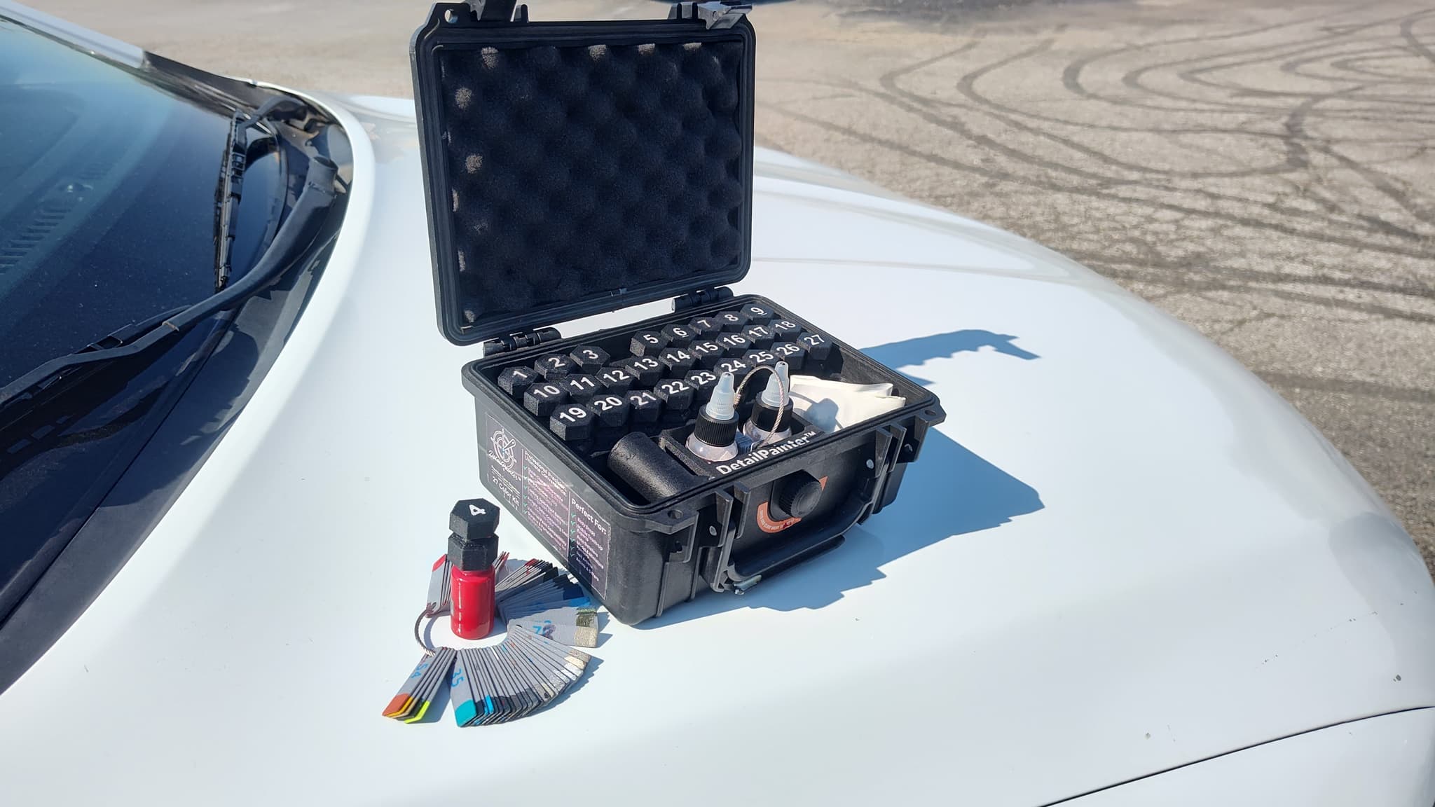 The numbered Touch Up Titans paint kit open on a hood, with the color swatch deck... 27 bottles the app calls by number